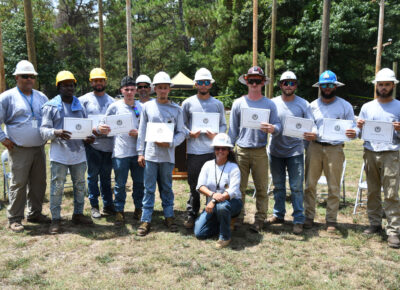 A group of people in gray shirts and hard hats.