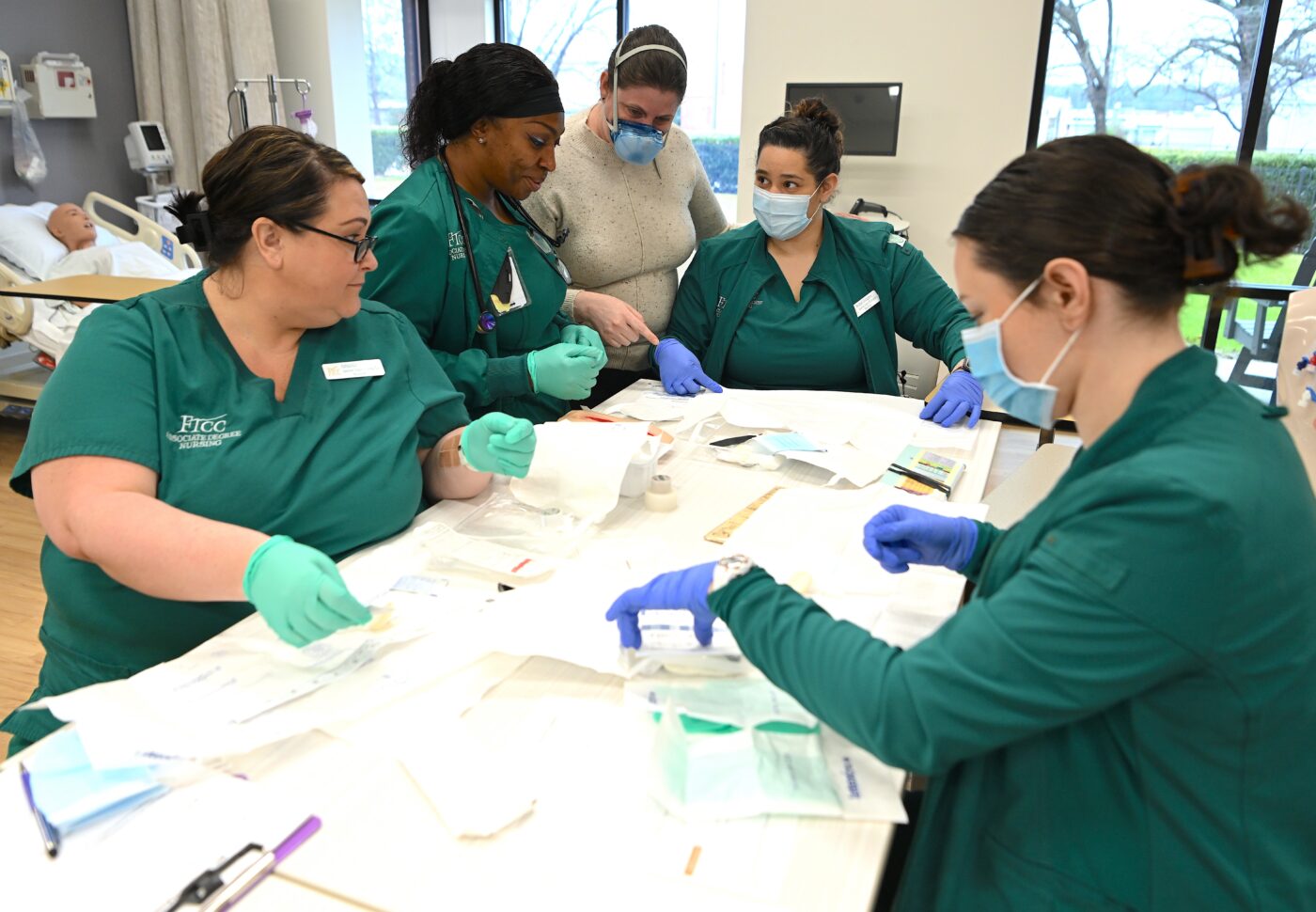 Healthcare students in green scrubs working together at a table.