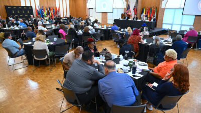 A room full of people seated at round tables.