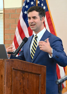 A man in a blue suit speaks at a podium.