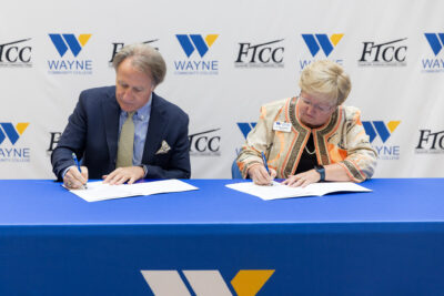 A man and a woman sign paperwork at a table.