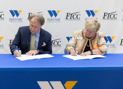 A man and a woman sign paperwork at a table.