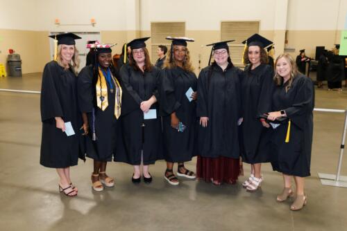 A group of graduates stand in a line to pose for a photo.