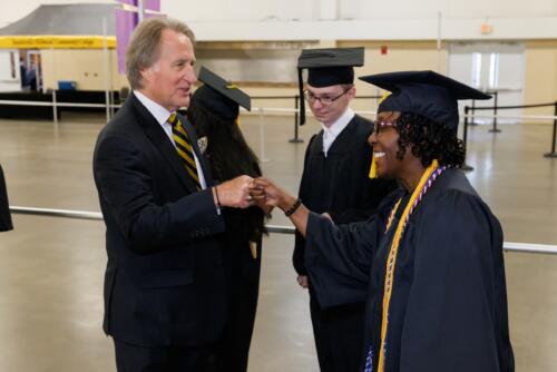 Dr. Mark Sorrells bumps fists with a graduate in the staging area before graduation.