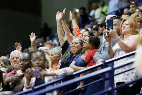 A group of women hold their hands up to wave at a graduate.