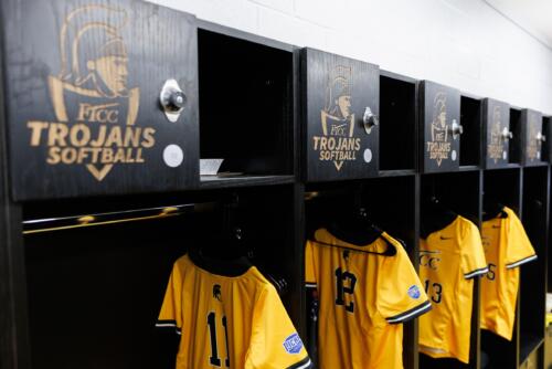 A row of lockers with jerseys hanging under them inside the fieldhouse.