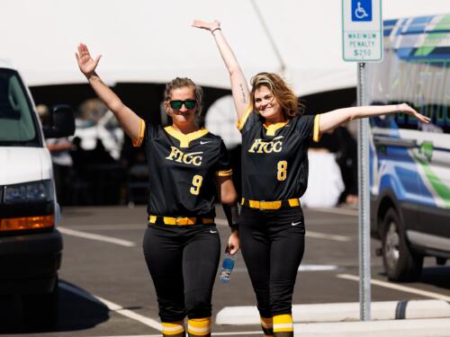 Softball players pose with their arms in the air for a picture before the game.