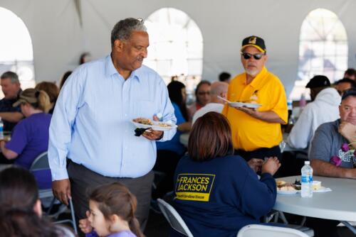 Glenn Adams and softball coach John Newman talk with VIPs inside the lunch tent before the game.