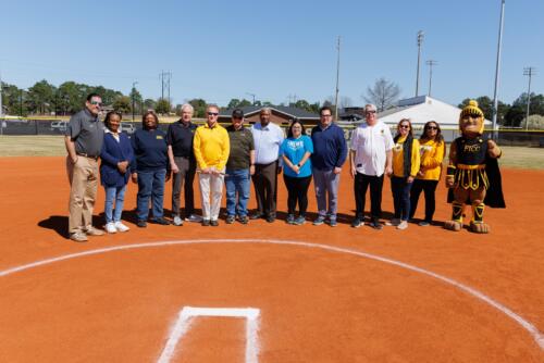 FTCC administration and community stakeholders pose for a photo before cutting the ribbon on the new field.