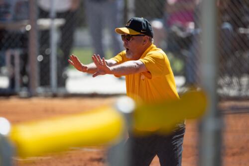 FTCC softball coach John Newman holds up both hands to tell a runner to stay.