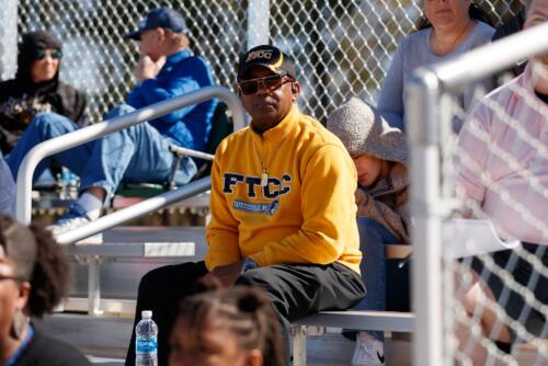 A Trojan softball fan watches the game from the stands.