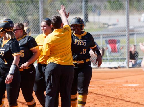 A FTCC player high fives a coach after the player scores a run.