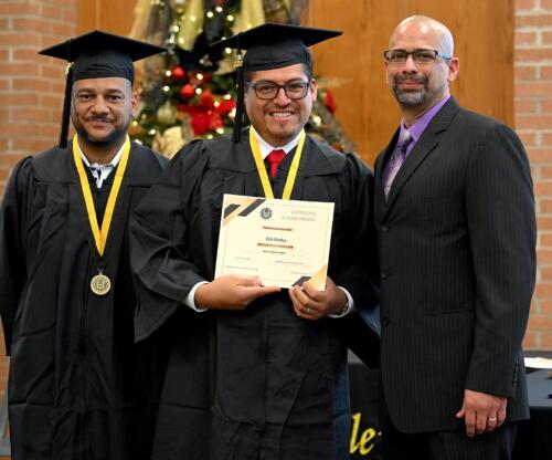 DA graduate poses with his certificate while standing next to Miguel Figueroa and his fellow graduate.